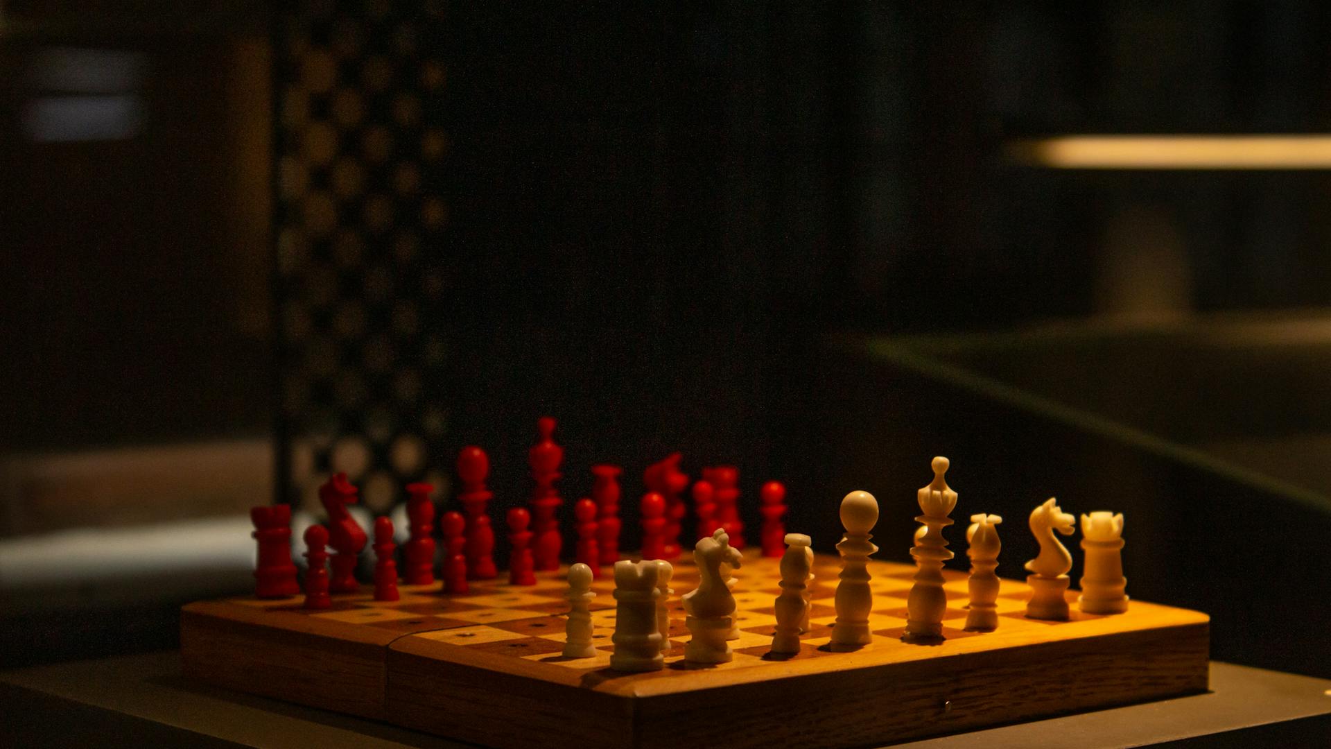 A beautifully lit chess game with red and white pieces, highlighting strategy and competition.