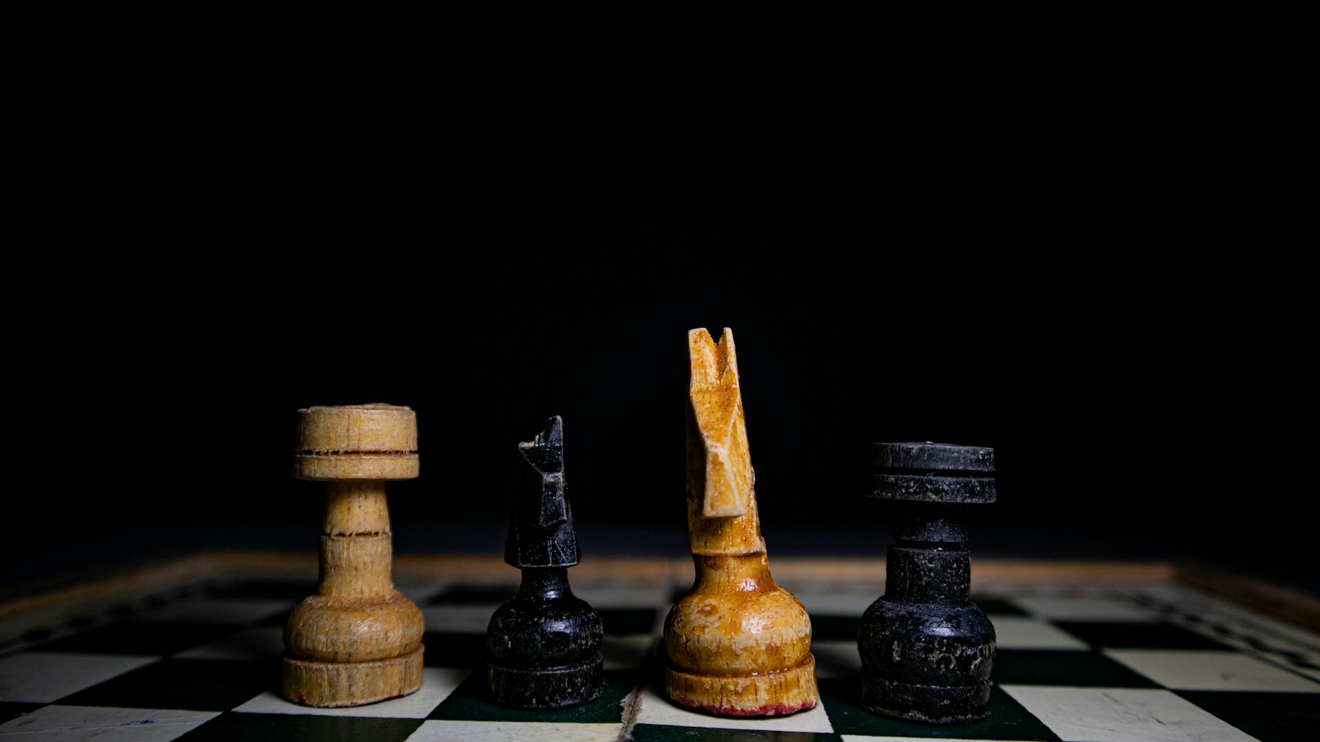 Close-up of rustic chess pieces on a wooden board, highlighting strategy and tactics.