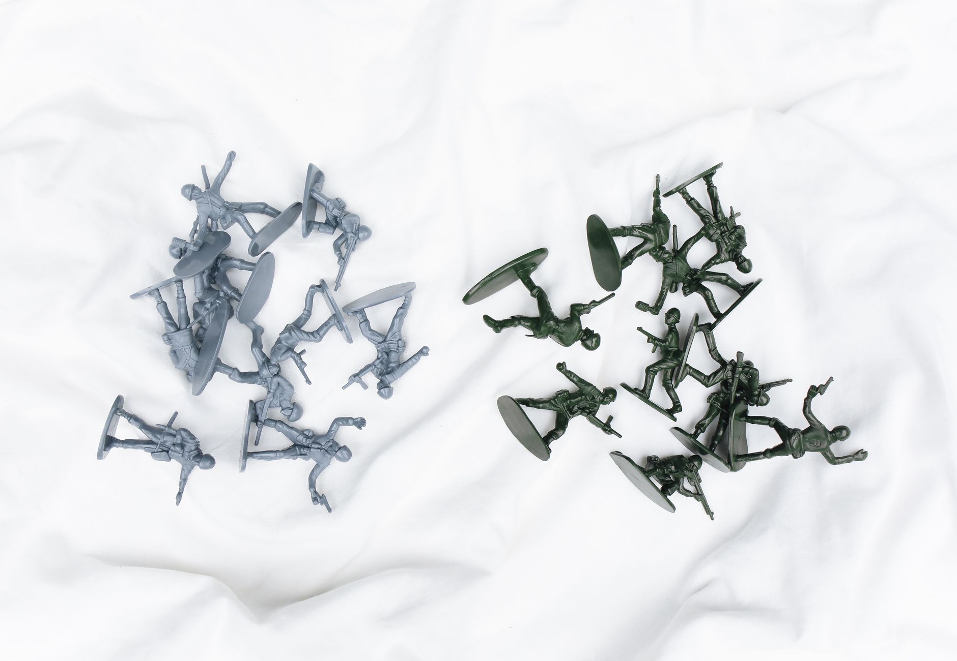 Colorful army toy figures arranged on a white cloth in aerial view.