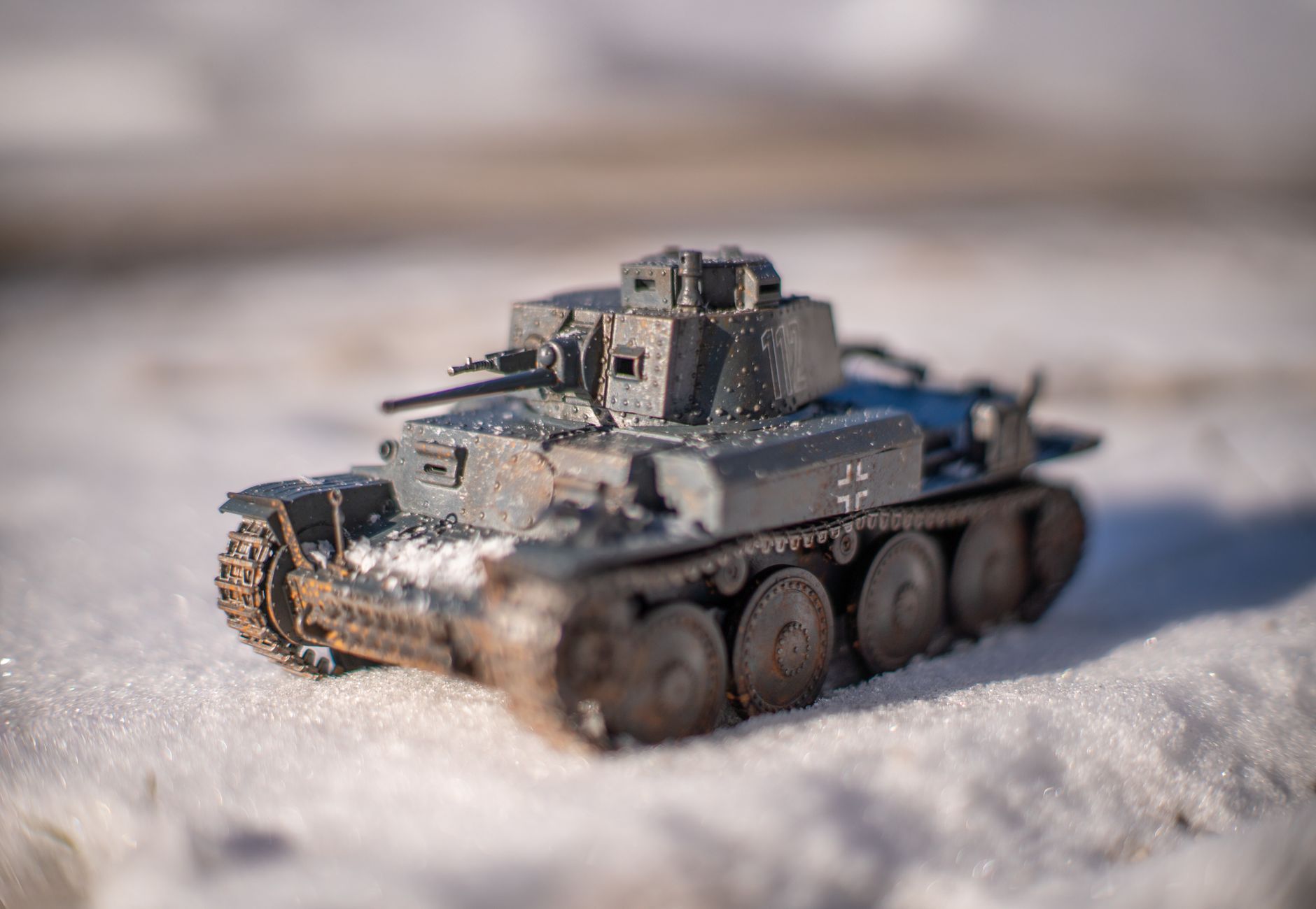 Close-up of a detailed WWII model tank positioned on snowy ground during winter day.