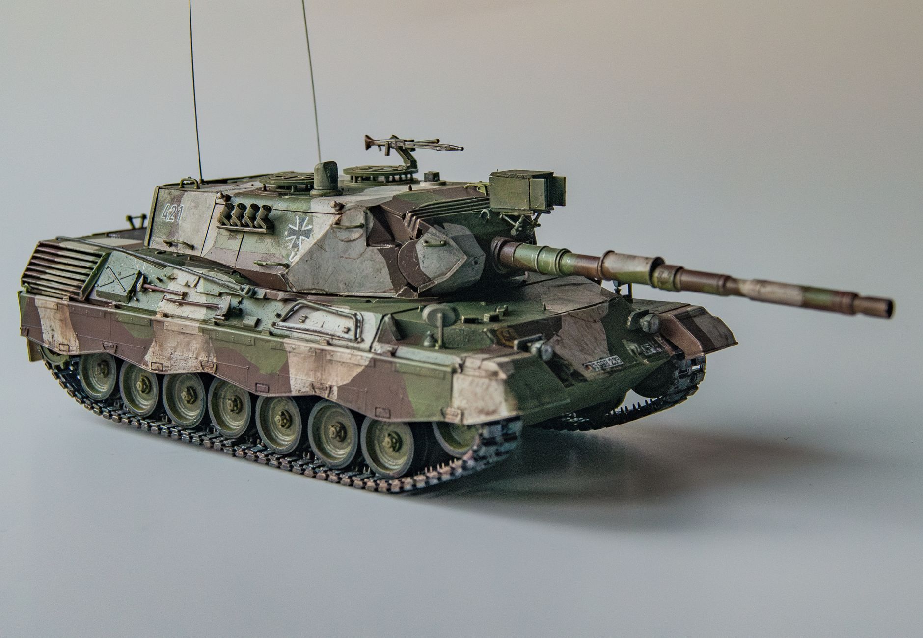 Close-up of a detailed model tank with camouflage paint in a studio setting, emphasizing military precision and design.