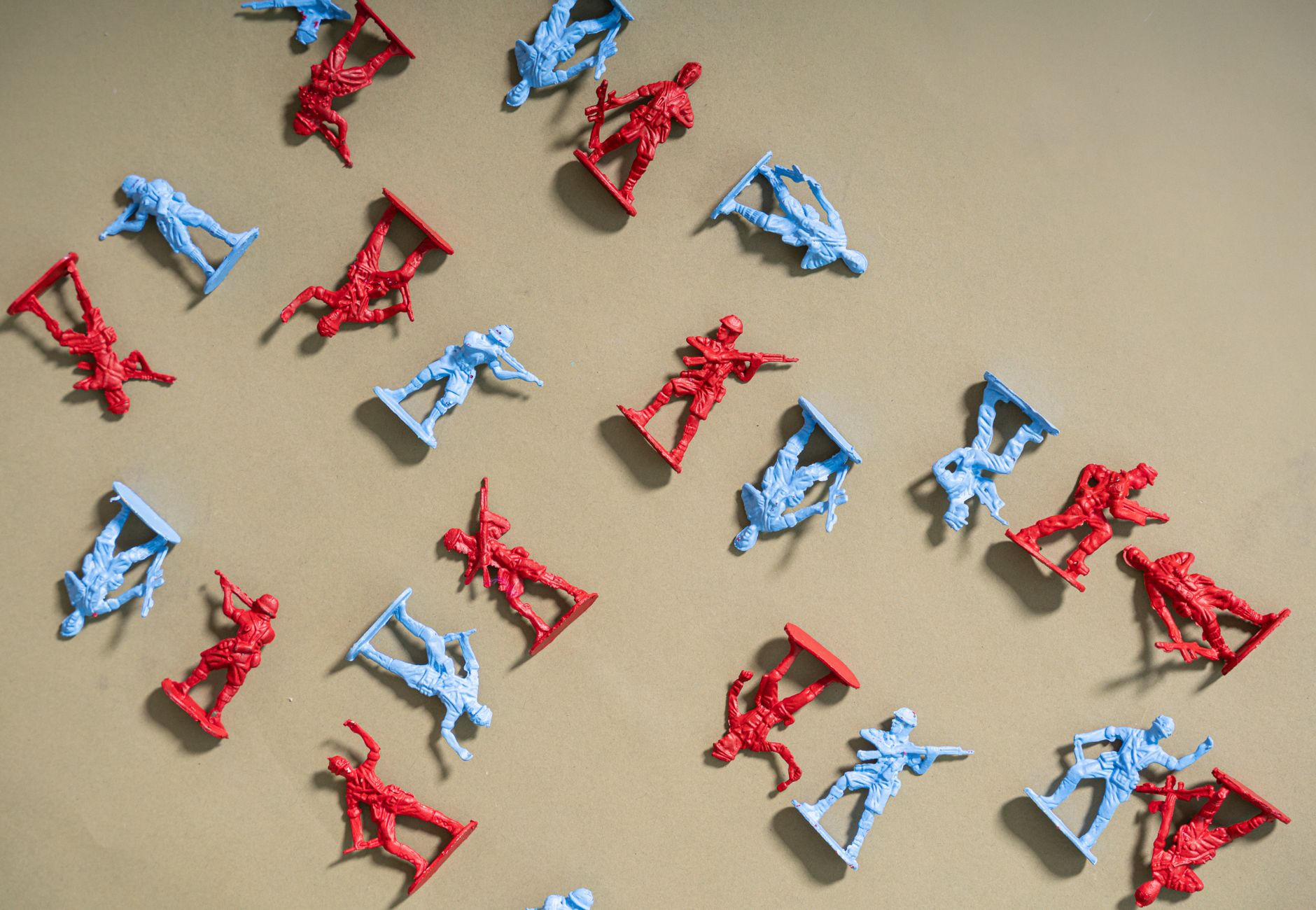Red and blue toy soldiers arranged on a beige background, artistic flat lay.