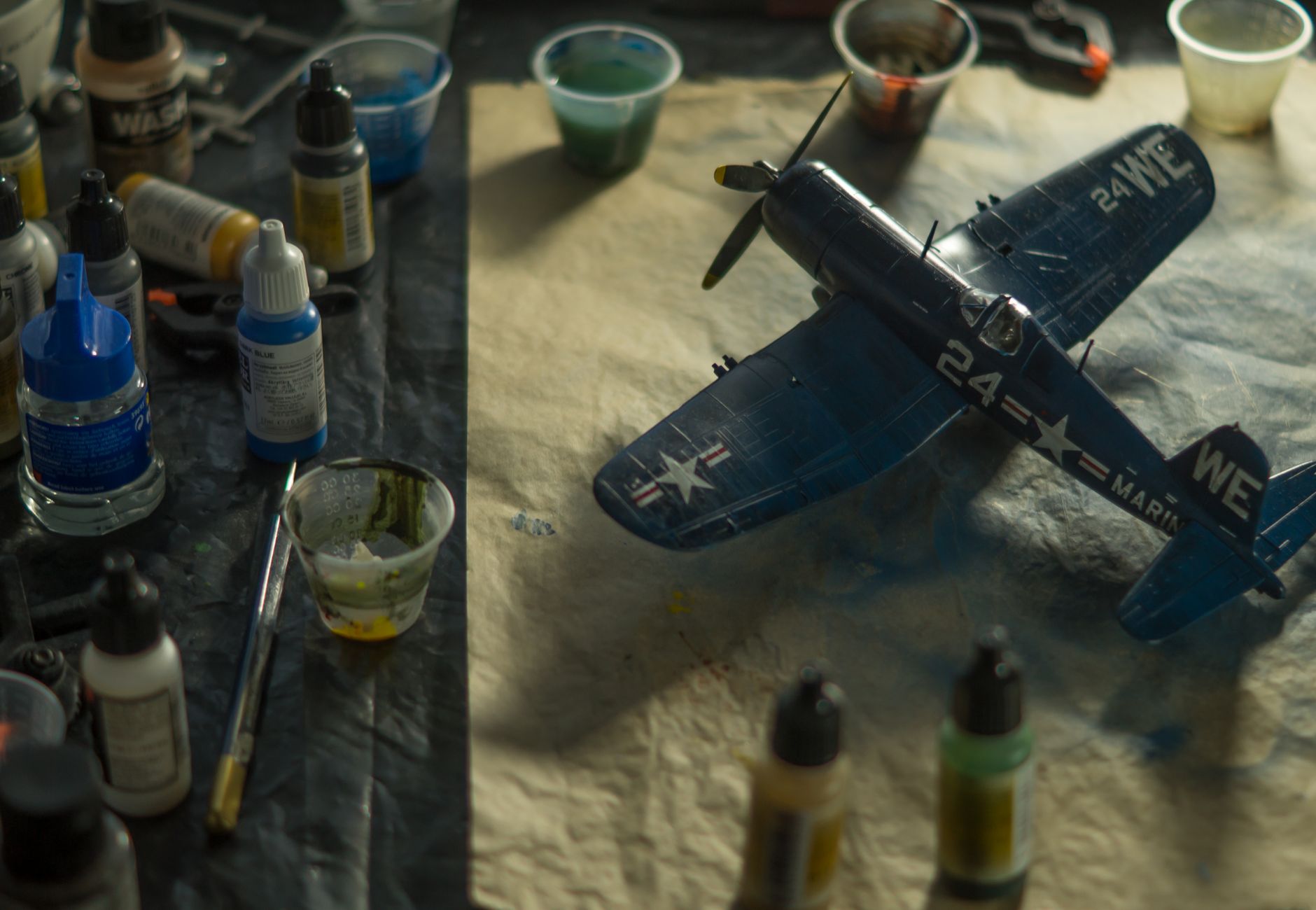 A model airplane surrounded by paints and brushes on a creative workspace.