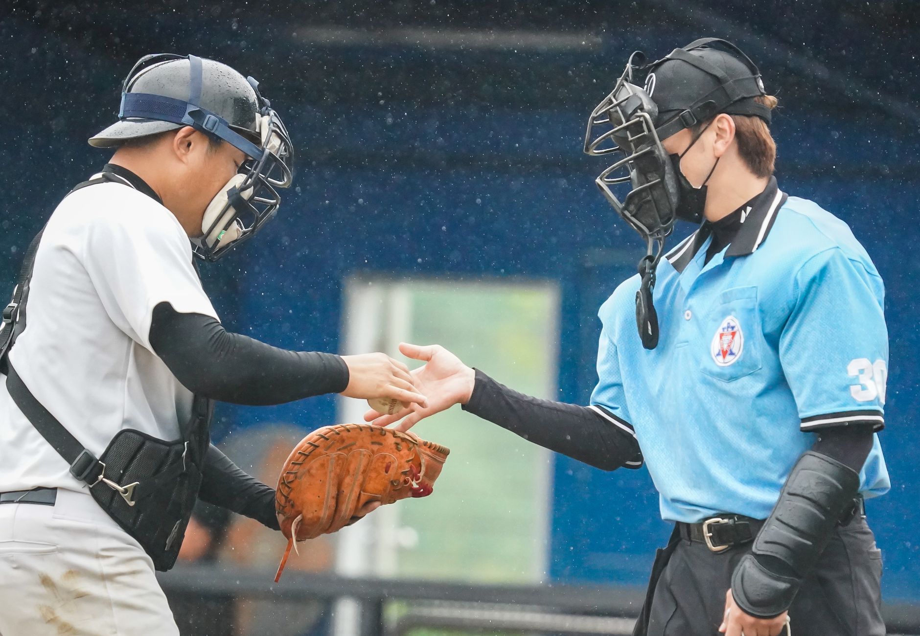 Baseball player shaking hands with an umpire on a rainy day.